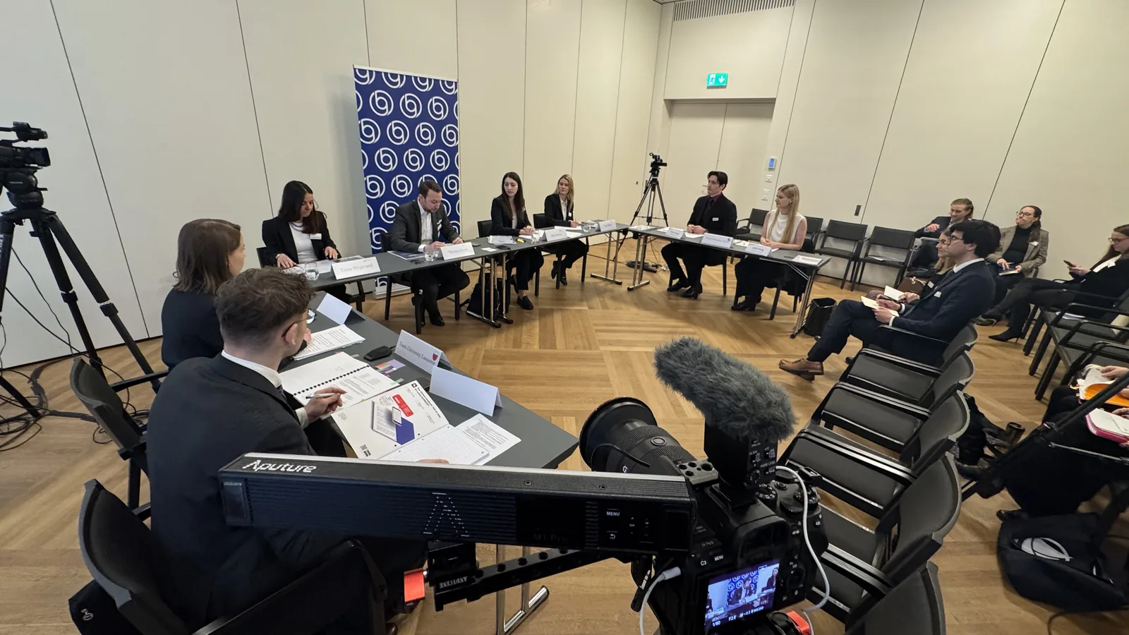 Mehrkamera-Setup bei der Dokumentation eines Anlasses: Podiumsrunde im Saal, Kamera und Richtmikrofon im Vordergrund