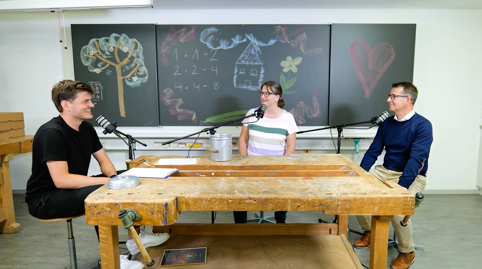 Gespräch im Schulzimmer mit Wandtafel im Hintergrund